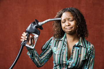 Wall Mural - Woman holding gas nozzle like a gun to her head