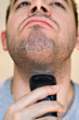 © ArenaCreative - A closeup of a young man shaving his beard off.