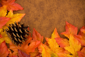 Wall Mural - Fall leaves with a pinecone on brown background, fall border