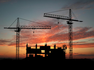 Wall Mural - Two cranes build construction over sunset