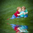 Young redheaded baby boys sitting outside on grass