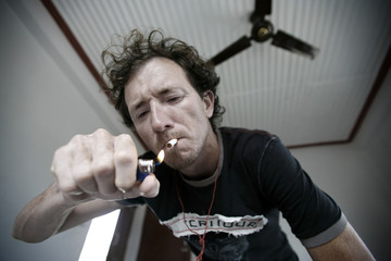 Young man lighting up a cigarette in hotel room