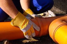 Closeup Of Plumber's Hands Assembling Pvc Sewage Pipes