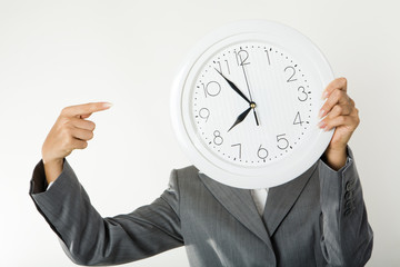 Image of female’s hands holding clock in front of face