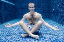 A Young Man Looking Relaxed Underwater In A Swimming Pool