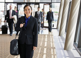 Fototapeta  - Happy businesswoman in full suit holding briefcase