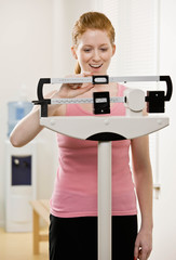 Woman checking dieting success by weighing herself on scale