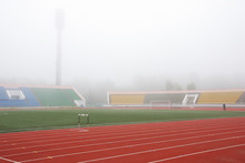 Red Running-tracks Of The Stadium Marked With White, In A Fog.