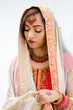 Elegant Bengali bride arranging veil looking down, isolated