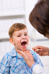 Wall Mural - Senior female doctor examining little child boy.