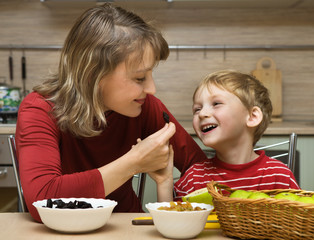 Wall Mural - Mother with son is eaten fruit in kitchen