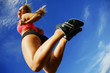 Beautiful woman leaping into air against sky, low angle.