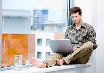 Poster - Businessman sitting in office window and working on laptop