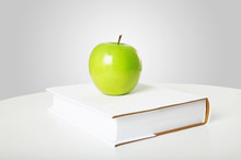 The Green Apple Is On The Book On A Grey Background