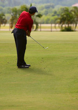 Man Making A Chip Shot Onto The Putting Green