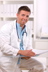 Wall Mural - Happy male doctor working at office, smiling.