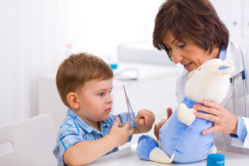 Wall Mural - Senior female  pediatrician playing with child