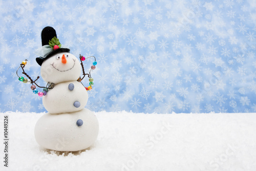 Fotografie, Obraz Snowman sitting on snow with snowflake background