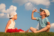 © Pavel Losevsky - Boy and girl sit on grass and drink from bottle