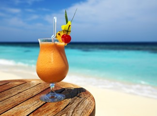 Bocal of fruity cocktail on a beach table