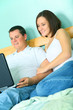 © visi.stock - Young Couple Using Laptop On Their Bed