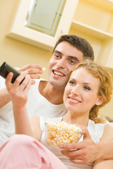 Canvas Print - Couple eating popcorn and watching TV together at home