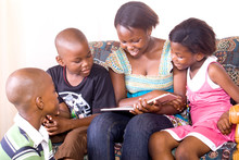 African Elder Sister Reading Story To Her Brother And Sister