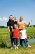 © Kzenon - Familie auf der Wiese vor dem Teich winkt