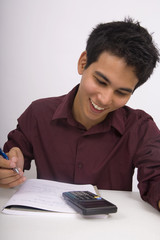 Asian American man doing his homework with a calculator