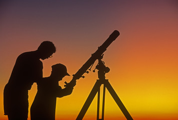 Wall Mural - a father demonstrates to his child how to use a telescope