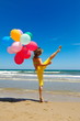 © bereta - young woman with colorful balloons jumping on the beach