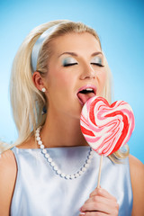 Wall Mural - Glamorous young woman licking lollypop