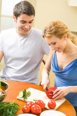 Canvas Print - Young couple cooking together with vegetables at home