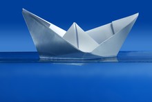 Paper Boat Floating Over Blue Real Water
