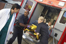 Paramedics And Doctor Unloading Patient From Ambulance