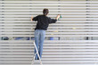 © fotofrank - Frau putzt Jaousie bei großem Fenster