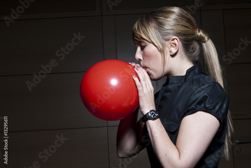 frau bläst einen roten luftballon auf Stock-Foto | Adobe Stock