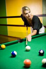 Beautiful blond woman playing billiards