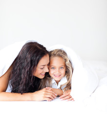 Wall Mural - Mother and daughter on bed smiling at camera