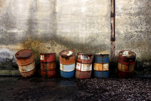 Abandones Rusty Steel Barrels In Front Of A Grungy Wall