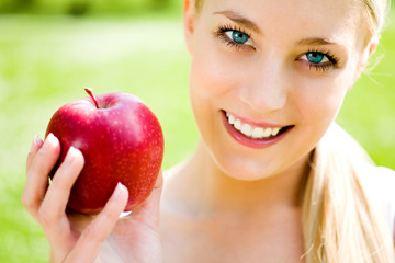 Young woman holding apple, smiling