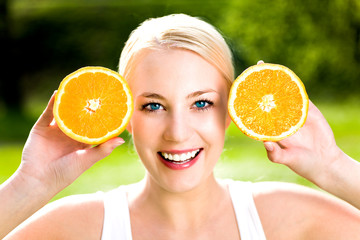 Woman holding two halves of orange