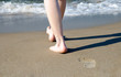 Frau läuft barfuß am Strand