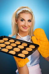 Wall Mural - Beautiful woman holding hot roasting pan with oat cookies on it.