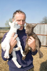 The portrait of farmer with two goatlings.