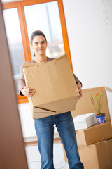 Canvas Print - Young woman lifting cardboard box