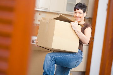 Wall Mural - Young woman lifting cardboard box