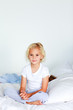 © WavebreakMediaMicro - Smiling blonde girl sitting on a bed