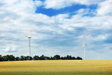 Wind turbines in a wheat field against a cloudy sky