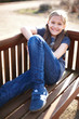 canvas print picture - fröhliches Mädchen sitzt auf einer Bank